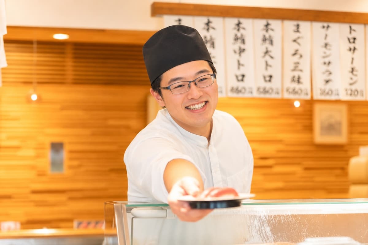 カウンターで寿司を握る笑顔の職人